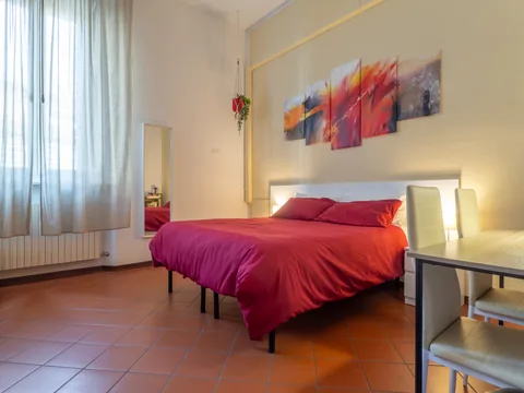 Schlafzimmer mit roter Tagesdecke und Schreibtisch